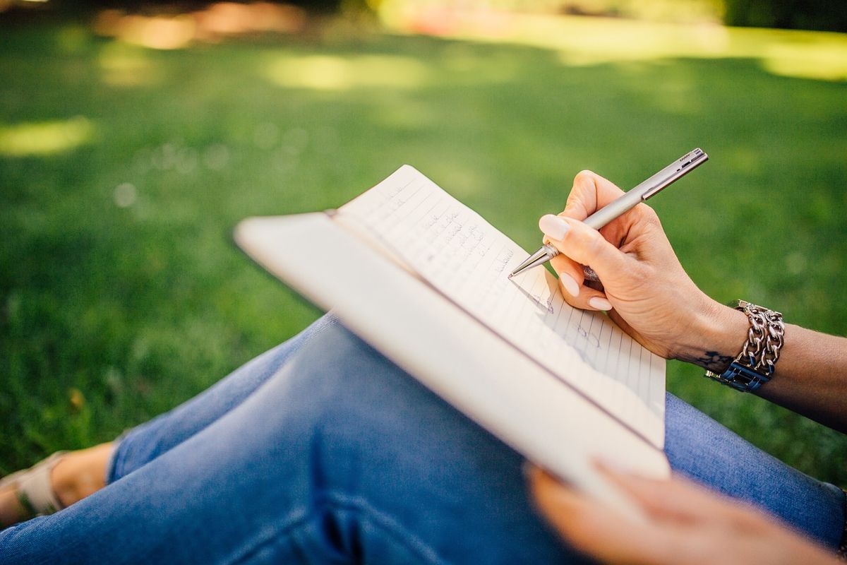 Woman writing in a notebook on the grass