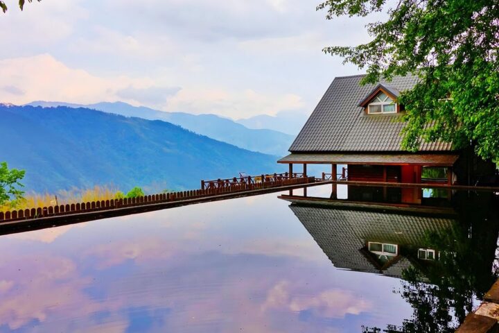 Infinity pool reflecting a modern house and mountains
