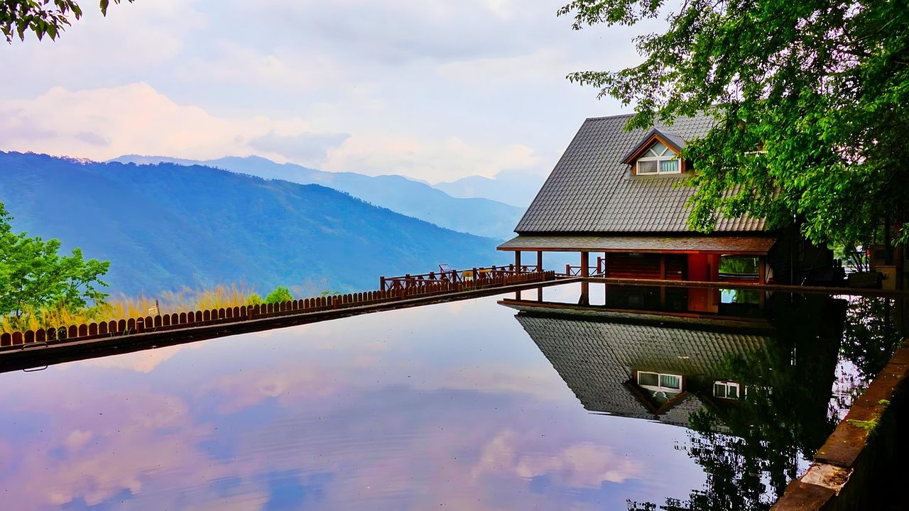 Infinity pool reflecting a modern house and mountains