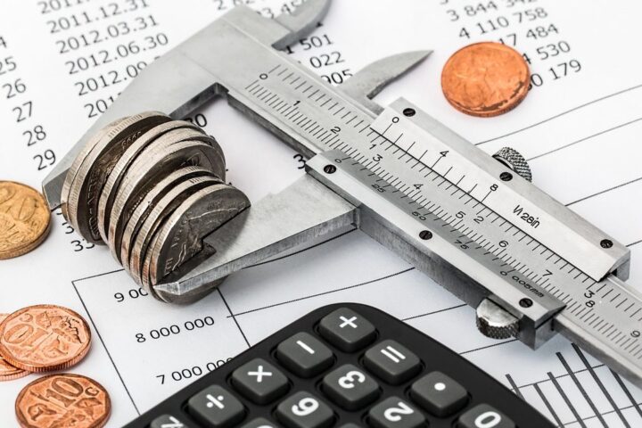 Calipers measuring a stack of coins on a calculator