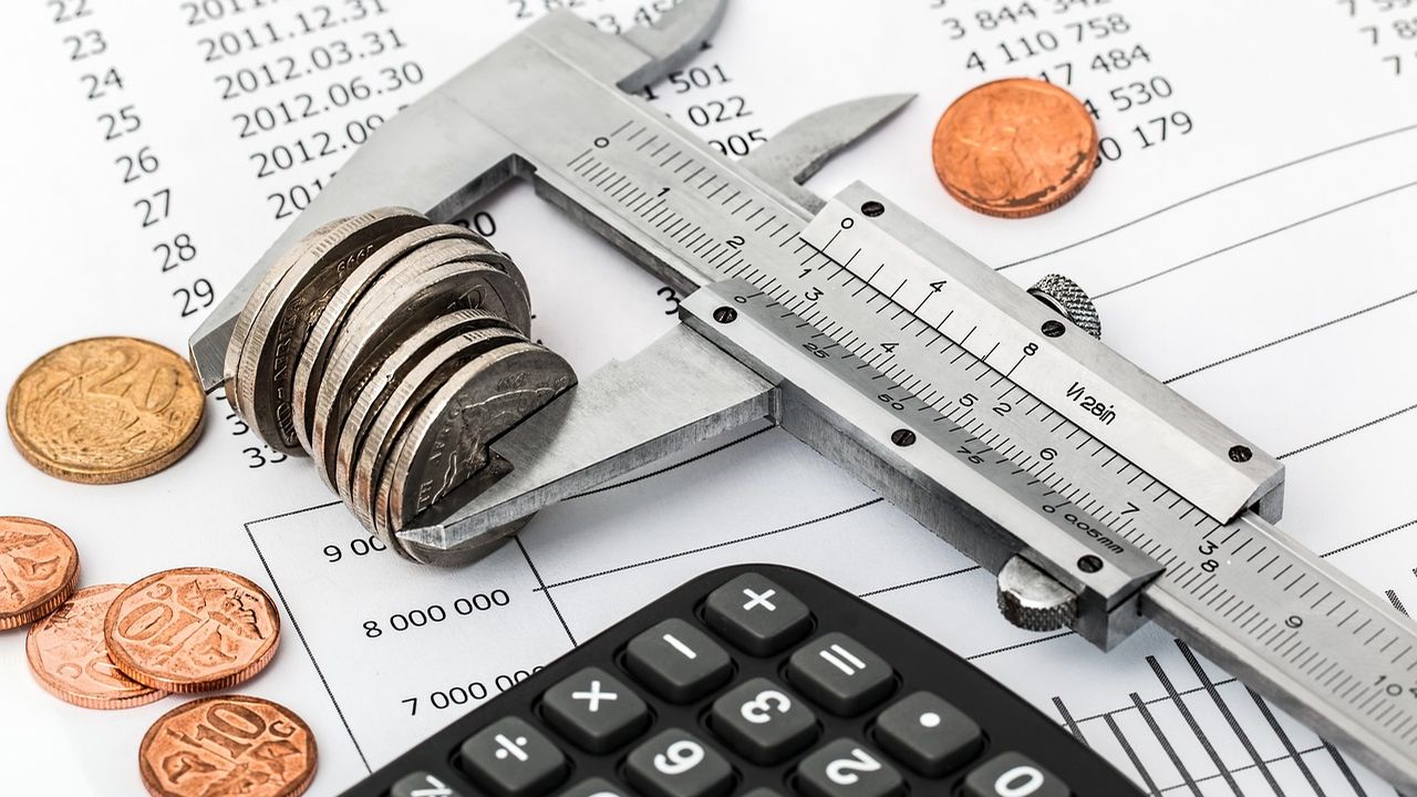Calipers measuring a stack of coins on a calculator