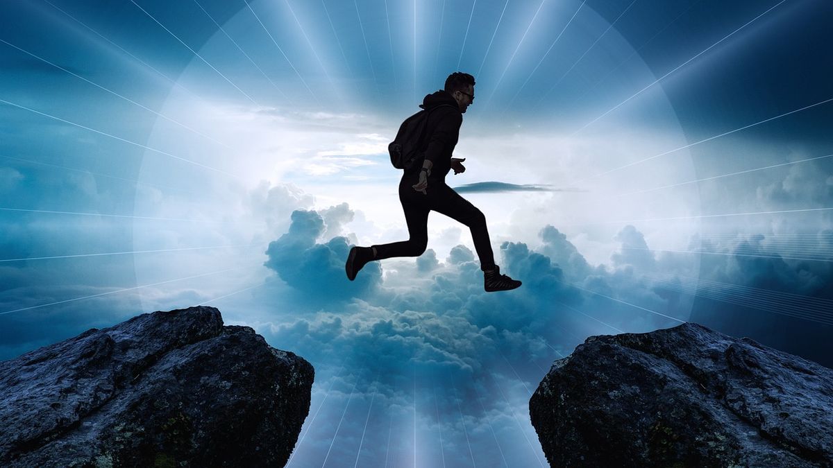 Man leaping across a gap between two cliffs