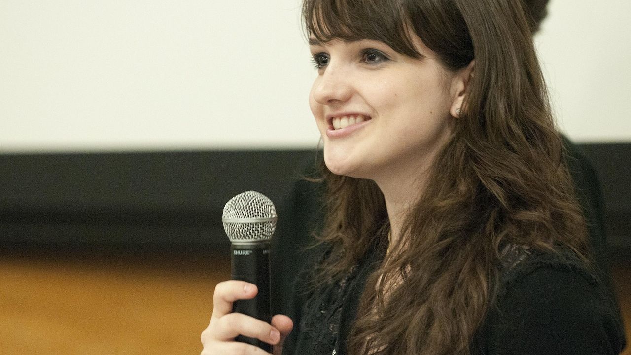 Woman speaking into a microphone at a conference