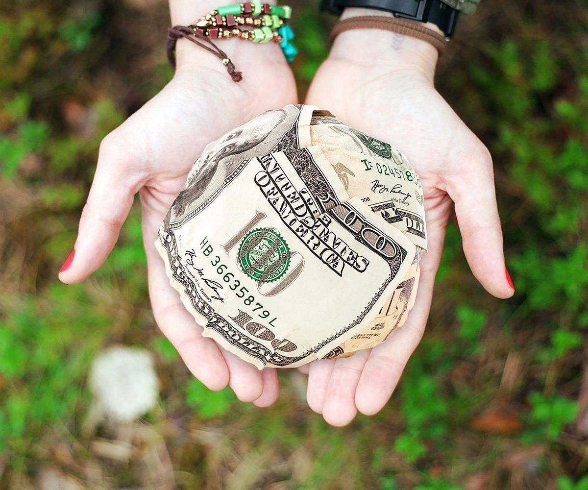 Cupped hands holding a folded banknote