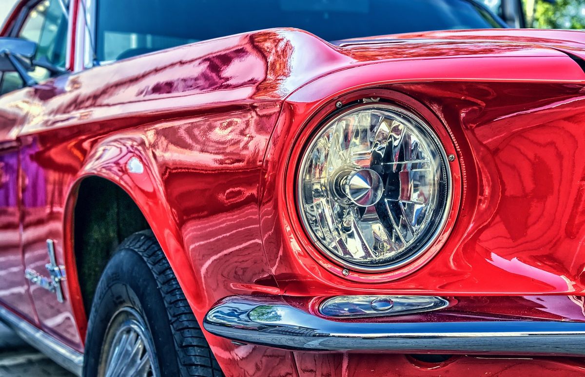 Close-up of the headlight of a glossy red classic car