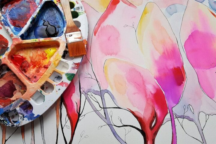 Artist's paint palette beside a bright watercolour painting
