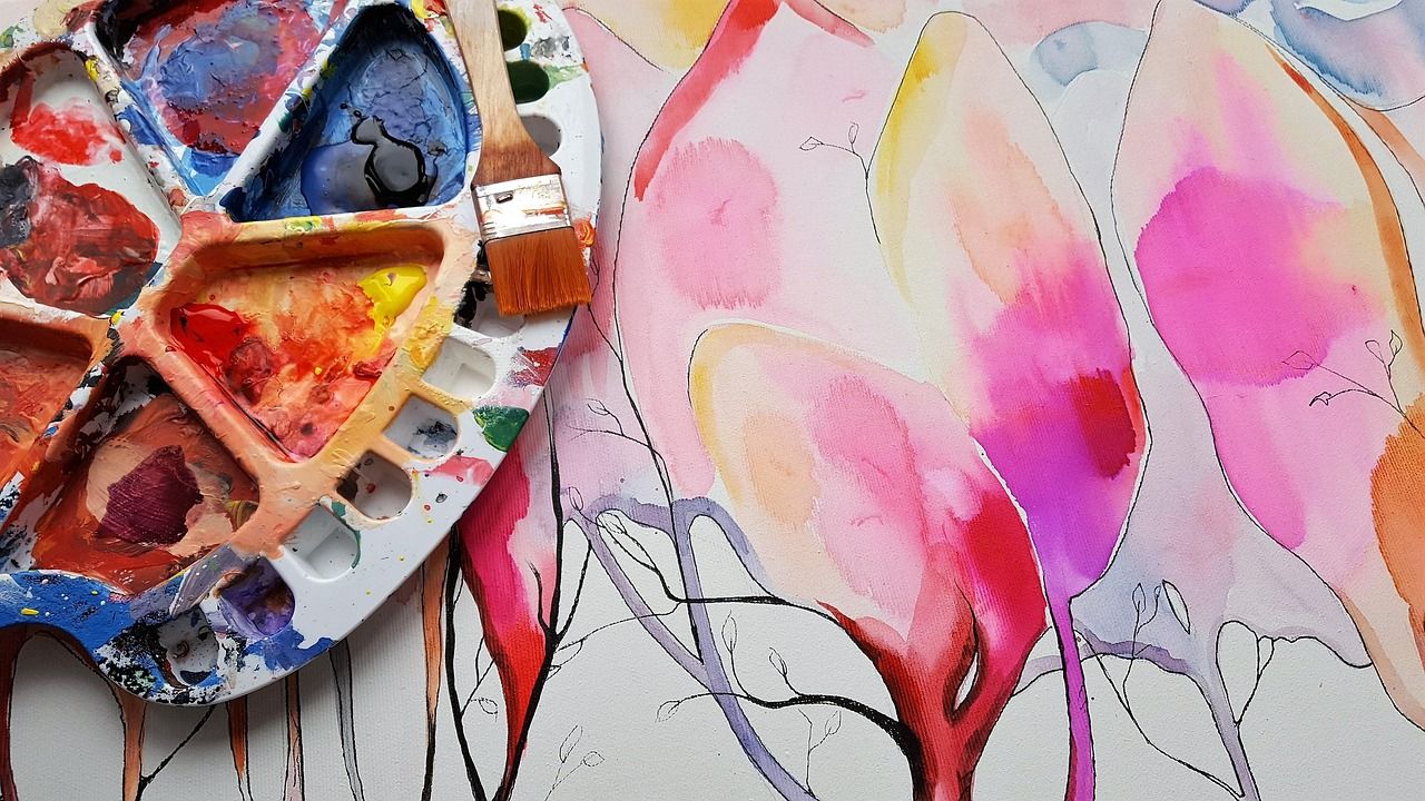 Artist's paint palette beside a bright watercolour painting