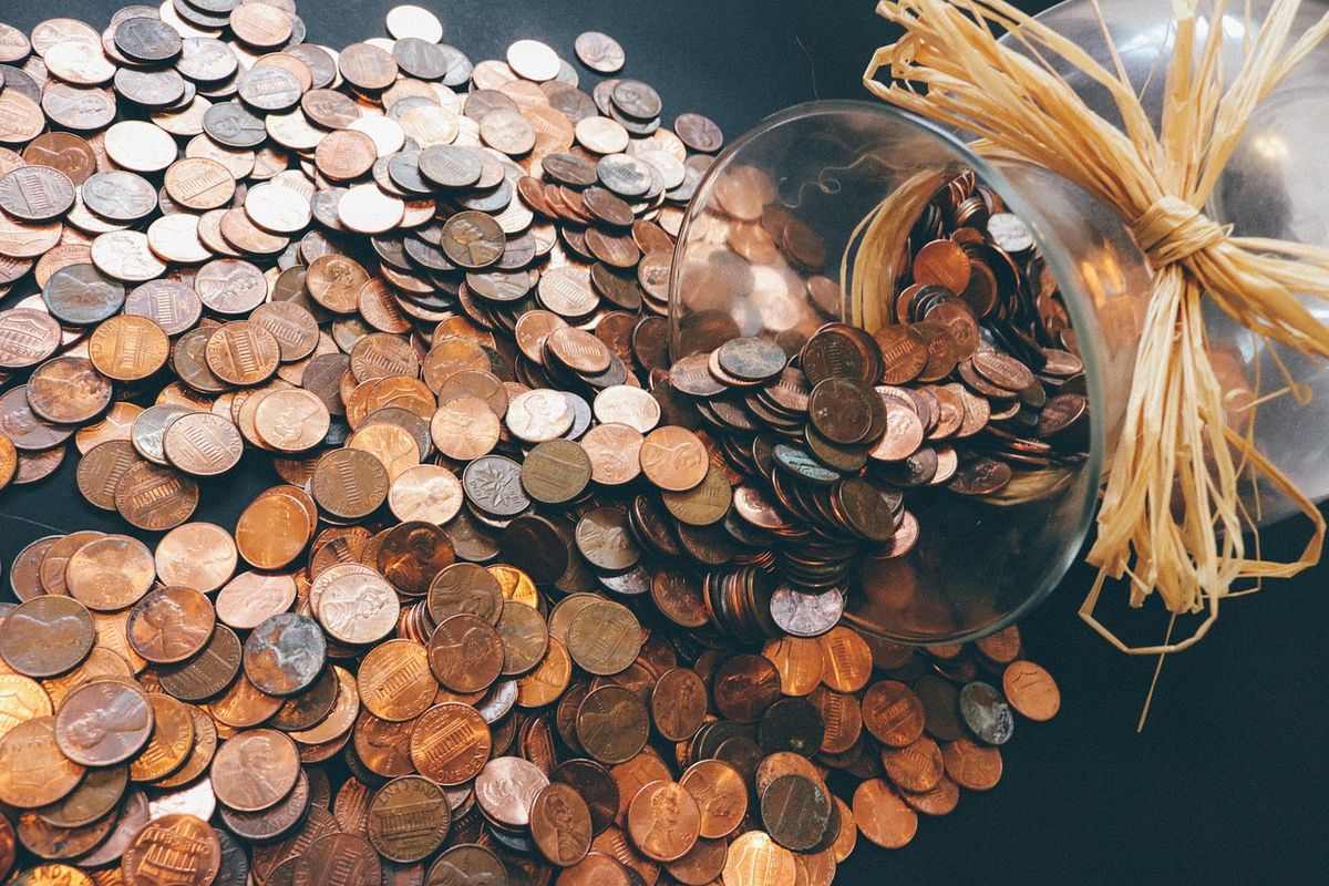 Glass jar tipped over spilling copper and silver coins