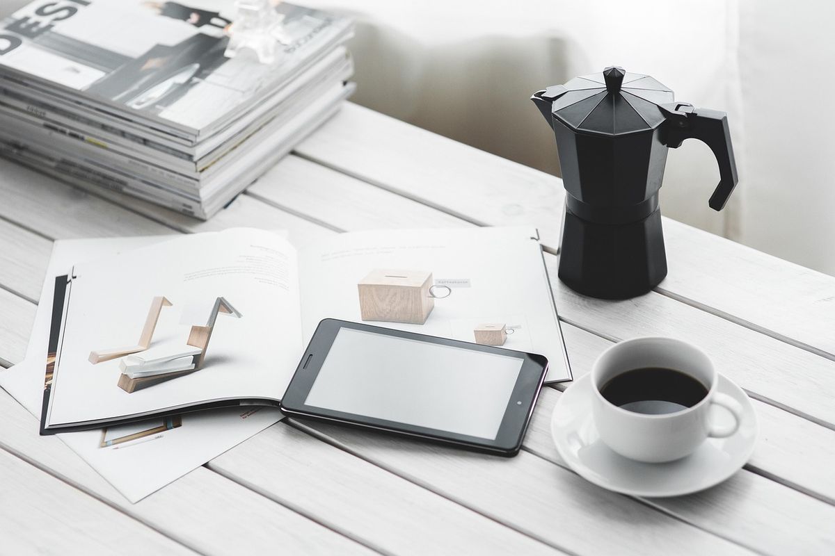 Tablet, coffee and magazines on a white table