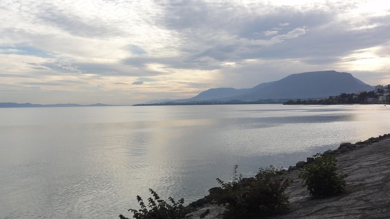 Calm lake with mountains under a cloudy sky