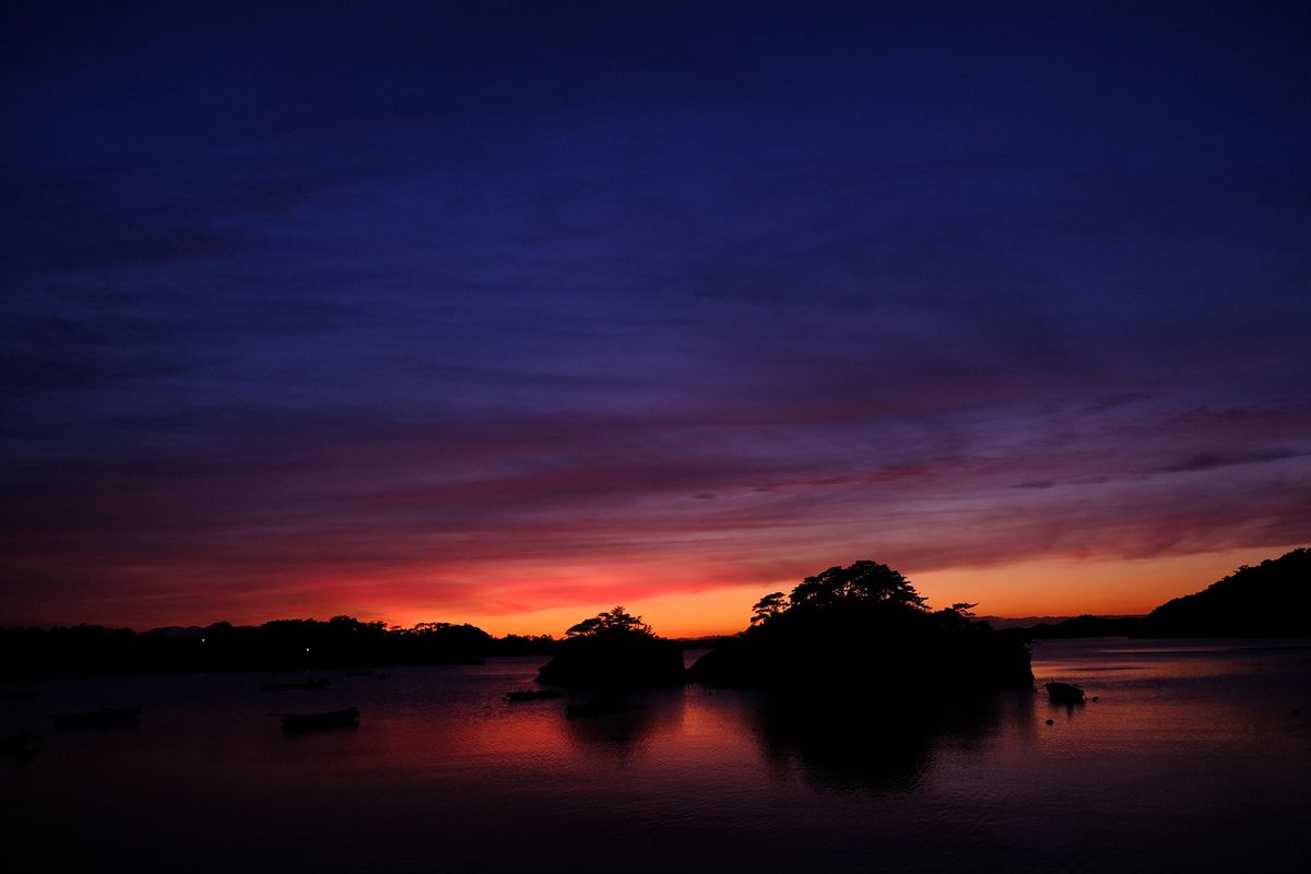 Sunset glowing over a still lake with silhouetted islands