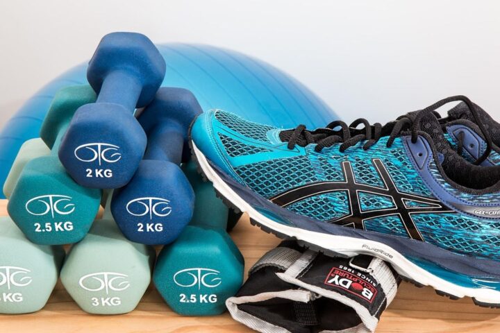 Dumbbells and running shoes beside an exercise ball