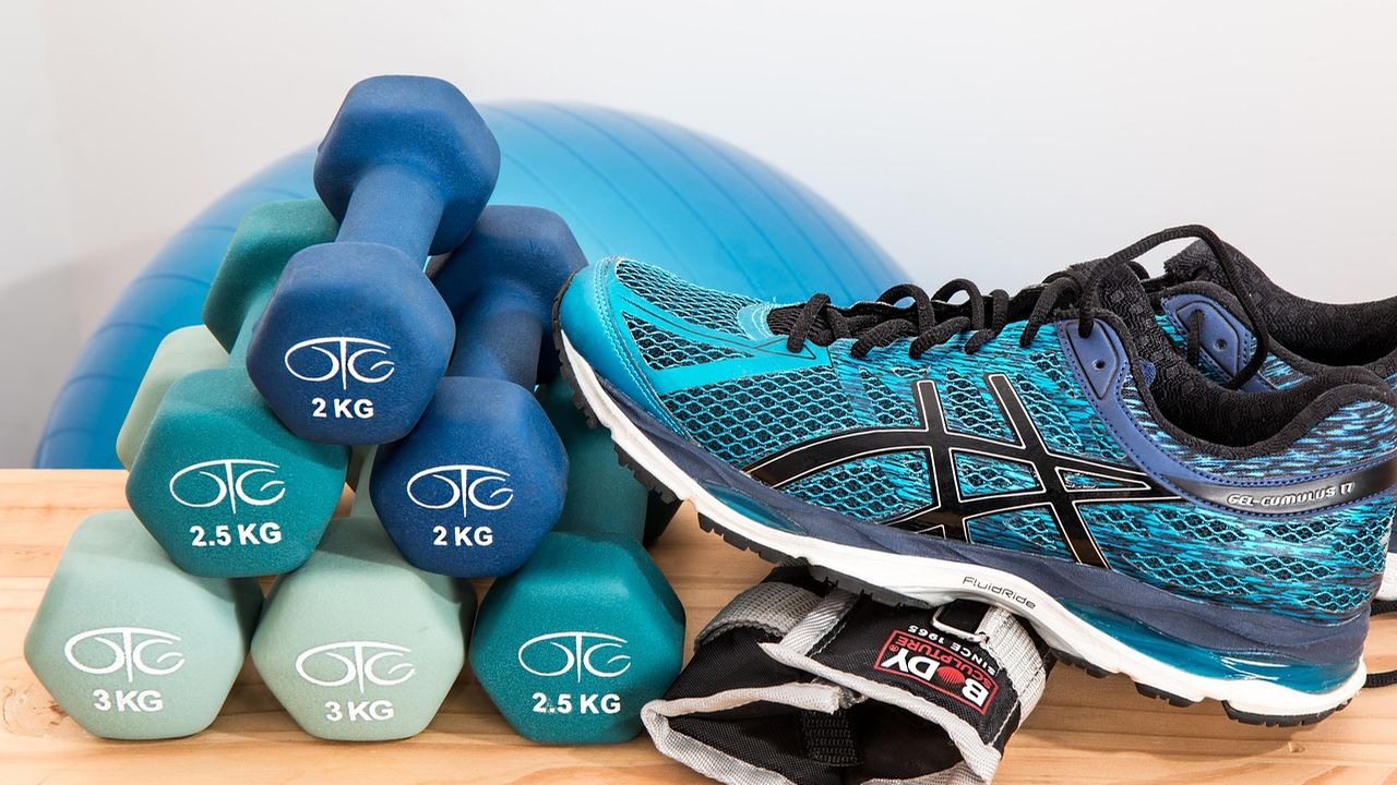 Dumbbells and running shoes beside an exercise ball