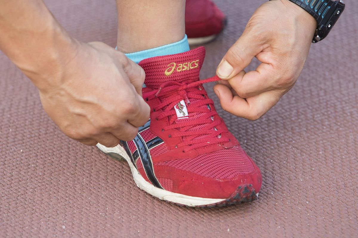 Runner tying the laces of a red trainer