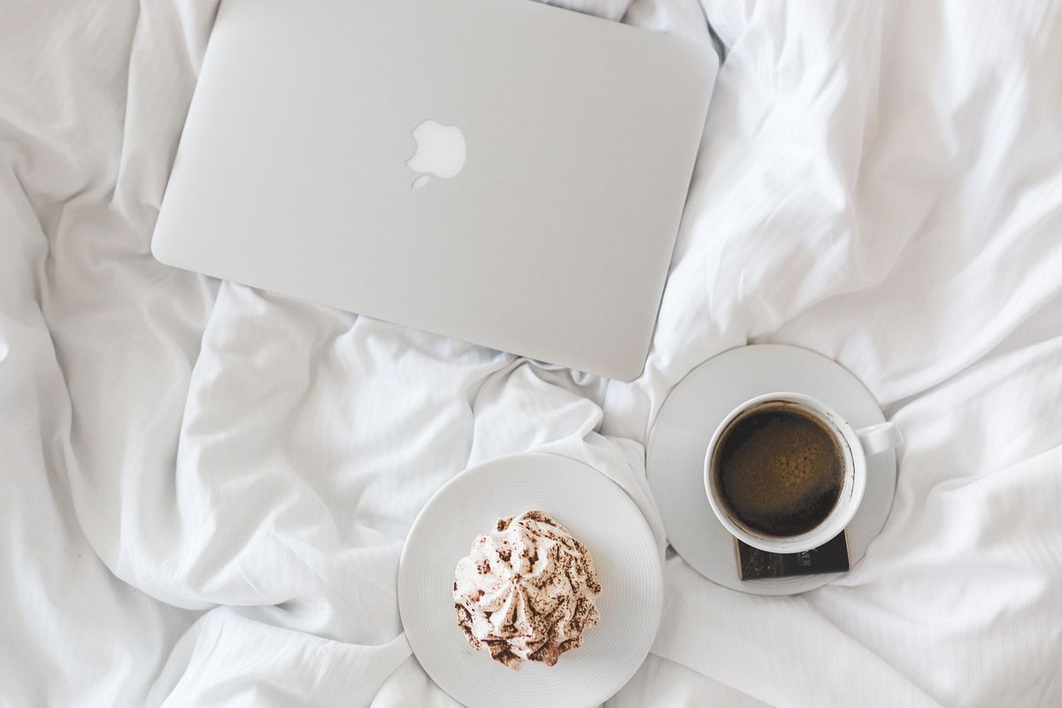 Laptop and coffee on a bed