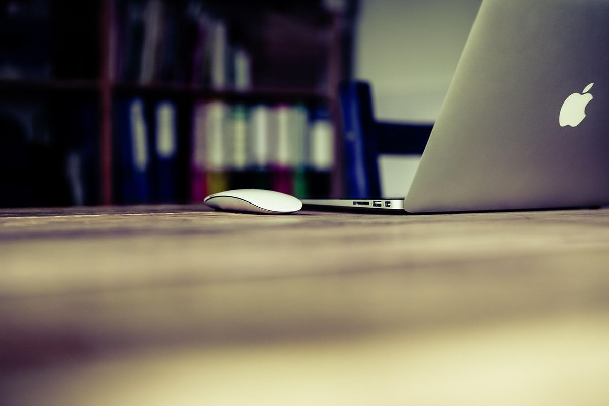 Laptop and mouse on a desk in a dim study