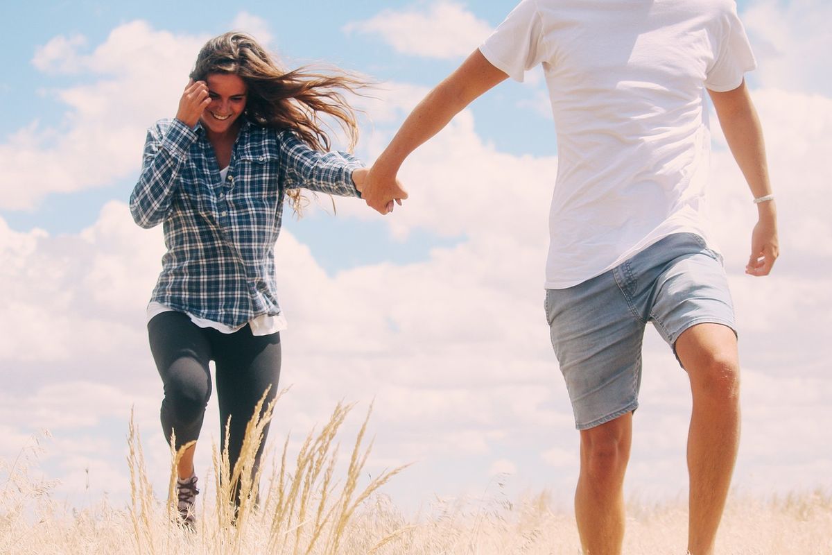Couple holding hands and running through long grass