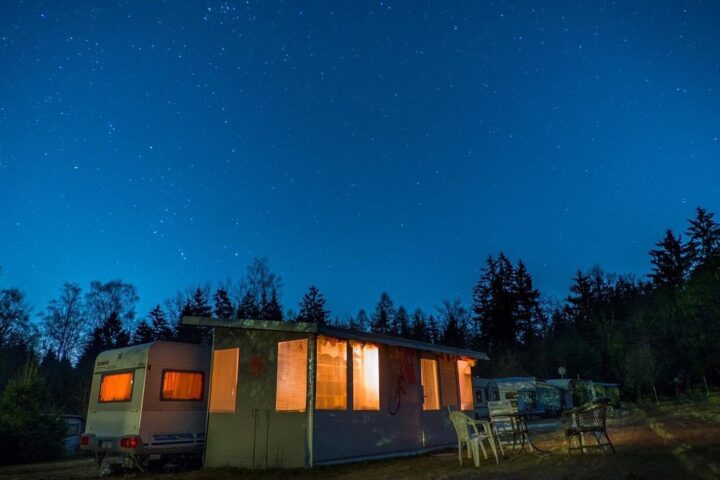 Caravan with glowing windows under a starry night sky