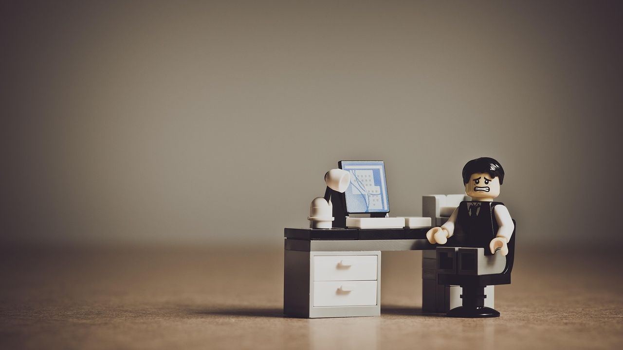 Toy office worker figure sitting at a tiny desk