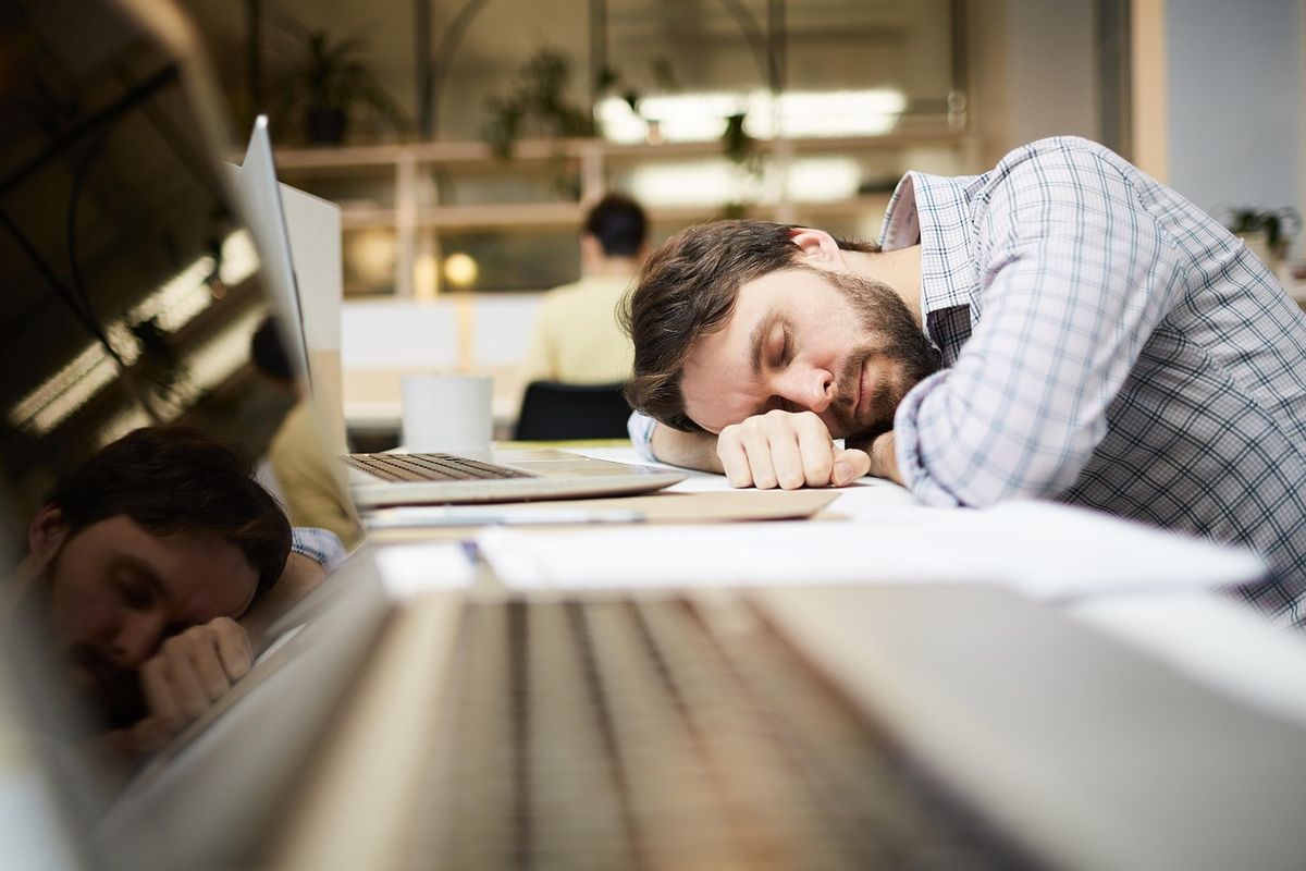 Office worker asleep with his head on his desk