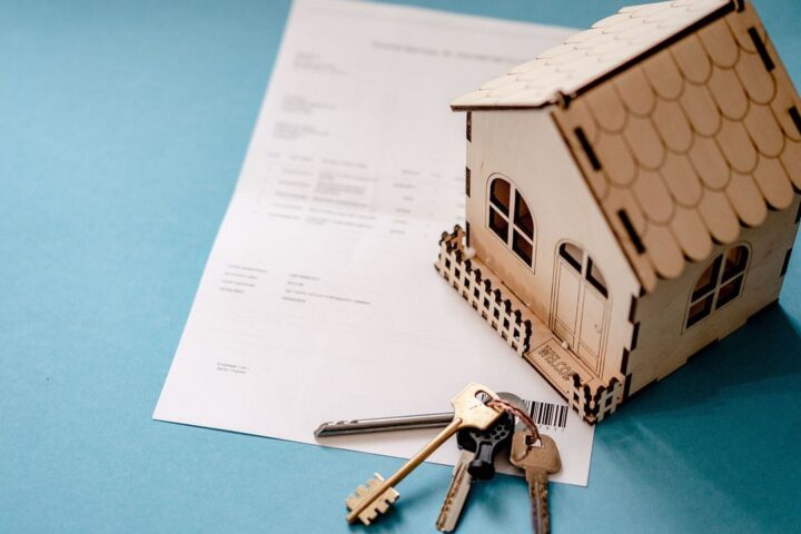 Model house, keys and a property contract on a desk