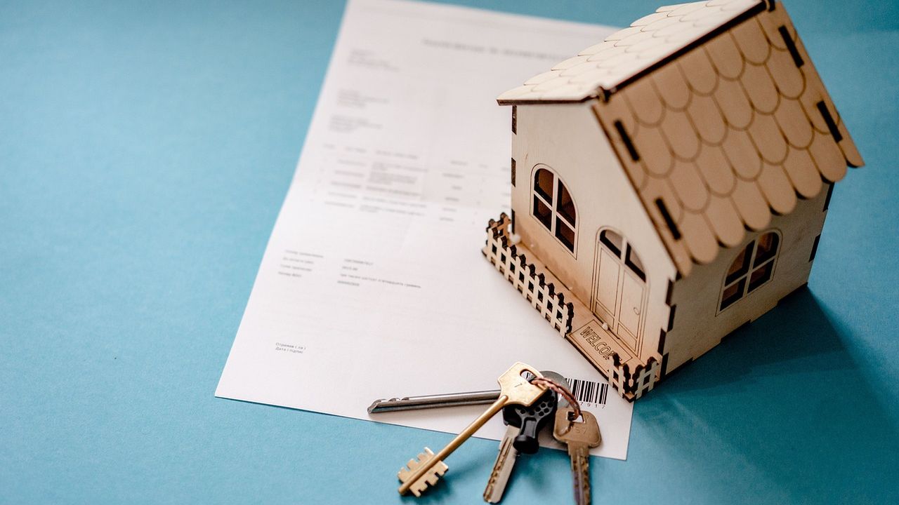Model house, keys and a property contract on a desk
