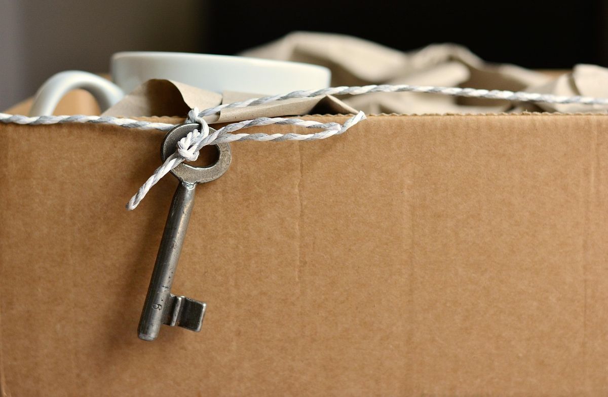 Old key tied to a cardboard moving box