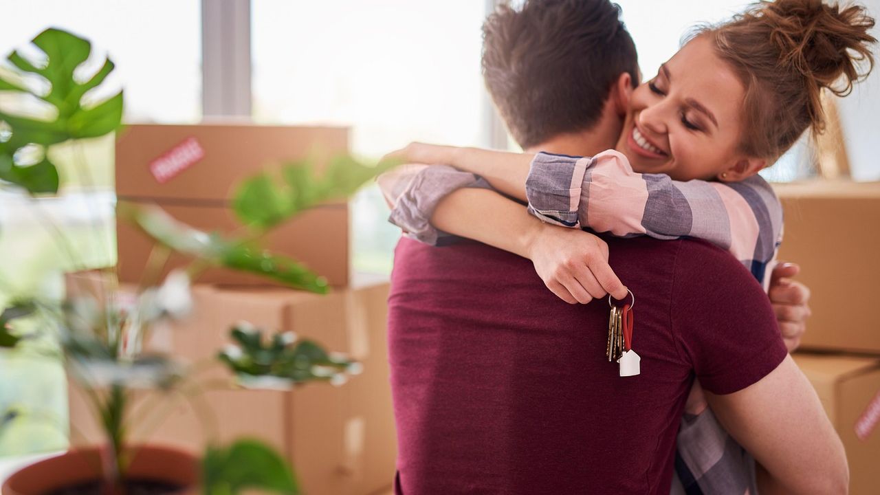 Couple hugging while holding the keys to their new home