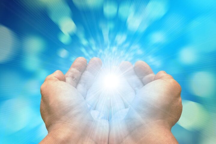 Cupped hands with a glowing burst of light between them