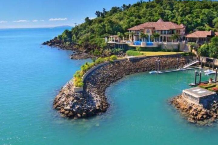 Aerial view of Mandalay House on a rocky headland by turquoise sea