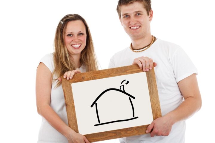 Young couple holding a drawing of a house