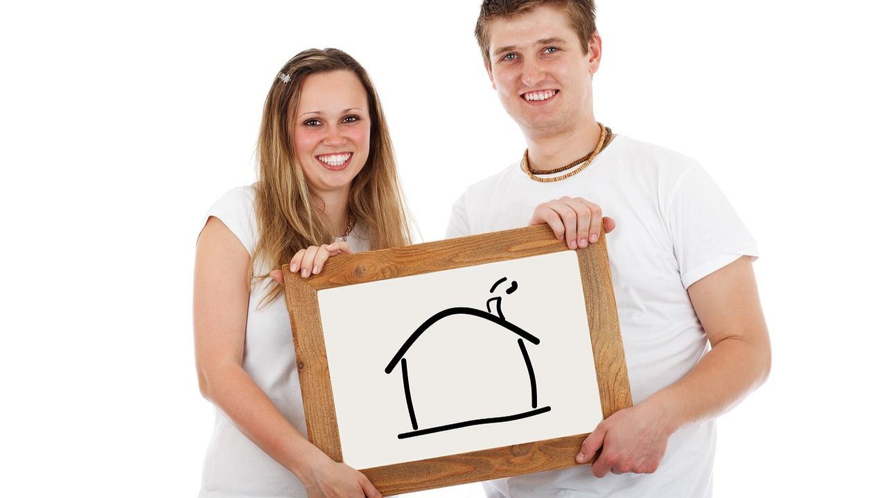 Young couple holding a drawing of a house