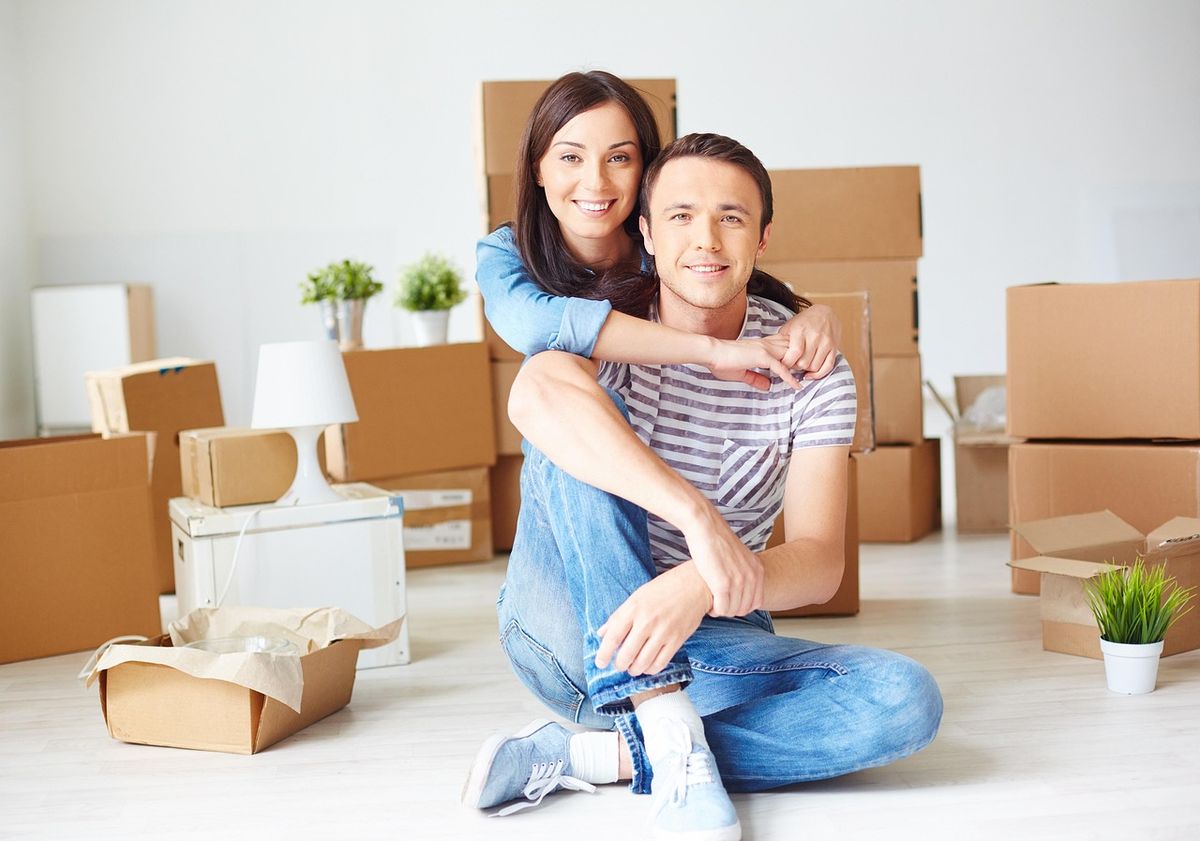 Happy couple sitting among moving boxes in their new home