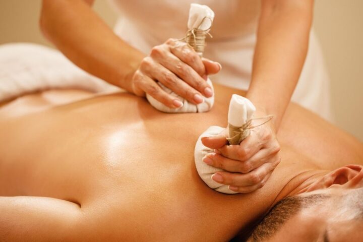 Therapist giving a back massage with herbal compresses