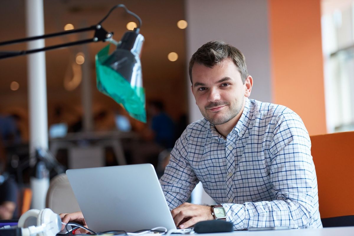Man smiling at his laptop in an office