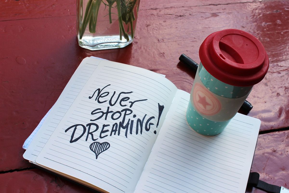 Notebook reading Never Stop Dreaming beside a coffee cup