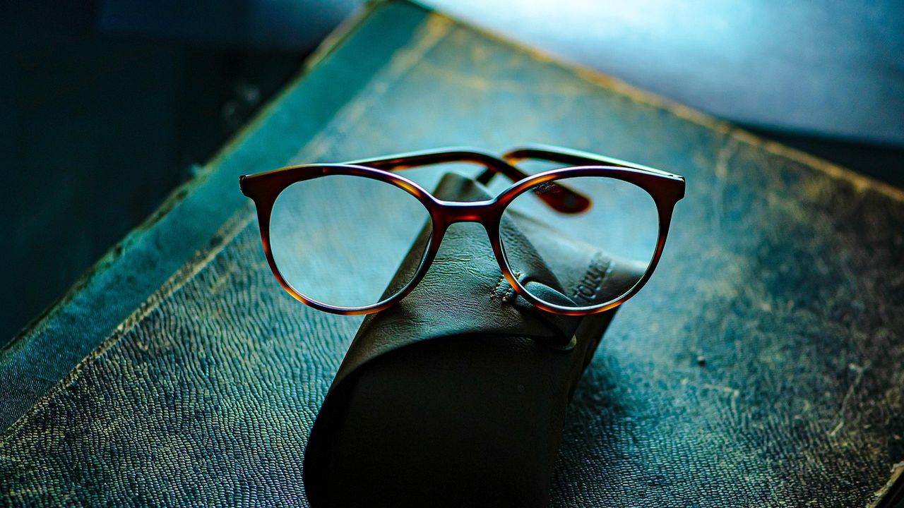 Pair of glasses on a teal surface