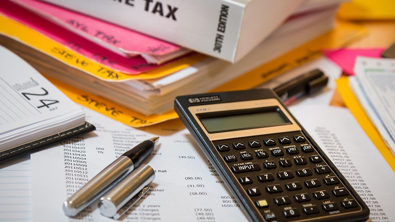 Tax paperwork, folders and a calculator on a desk