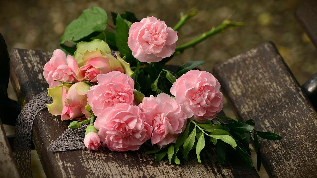 Bunch of pink roses resting on a wooden bench