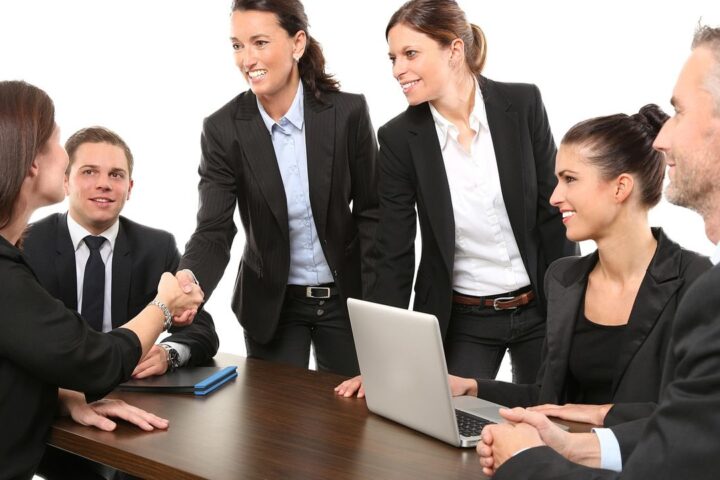 Businesswomen and businessmen shaking hands around a meeting table