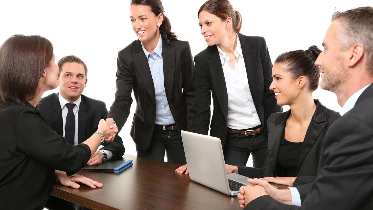 Businesswomen and businessmen shaking hands around a meeting table