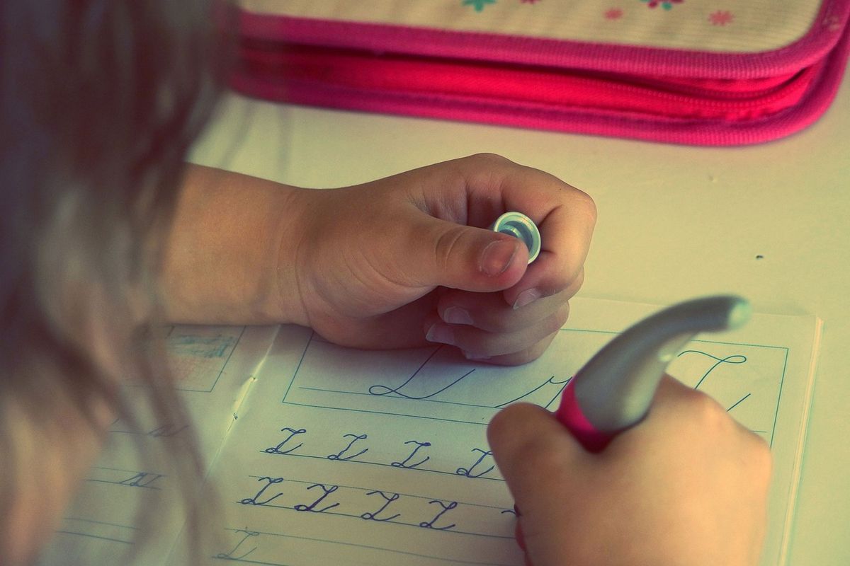 Child tracing letters on a worksheet