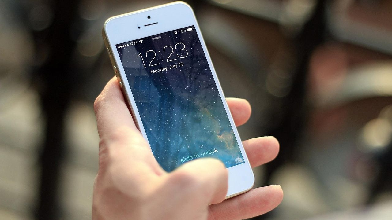 Hand holding a smartphone showing the lock screen