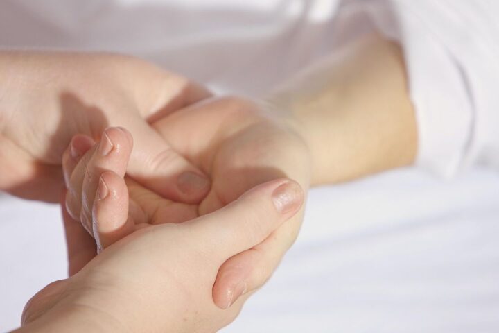 Therapist gently massaging a client's hand