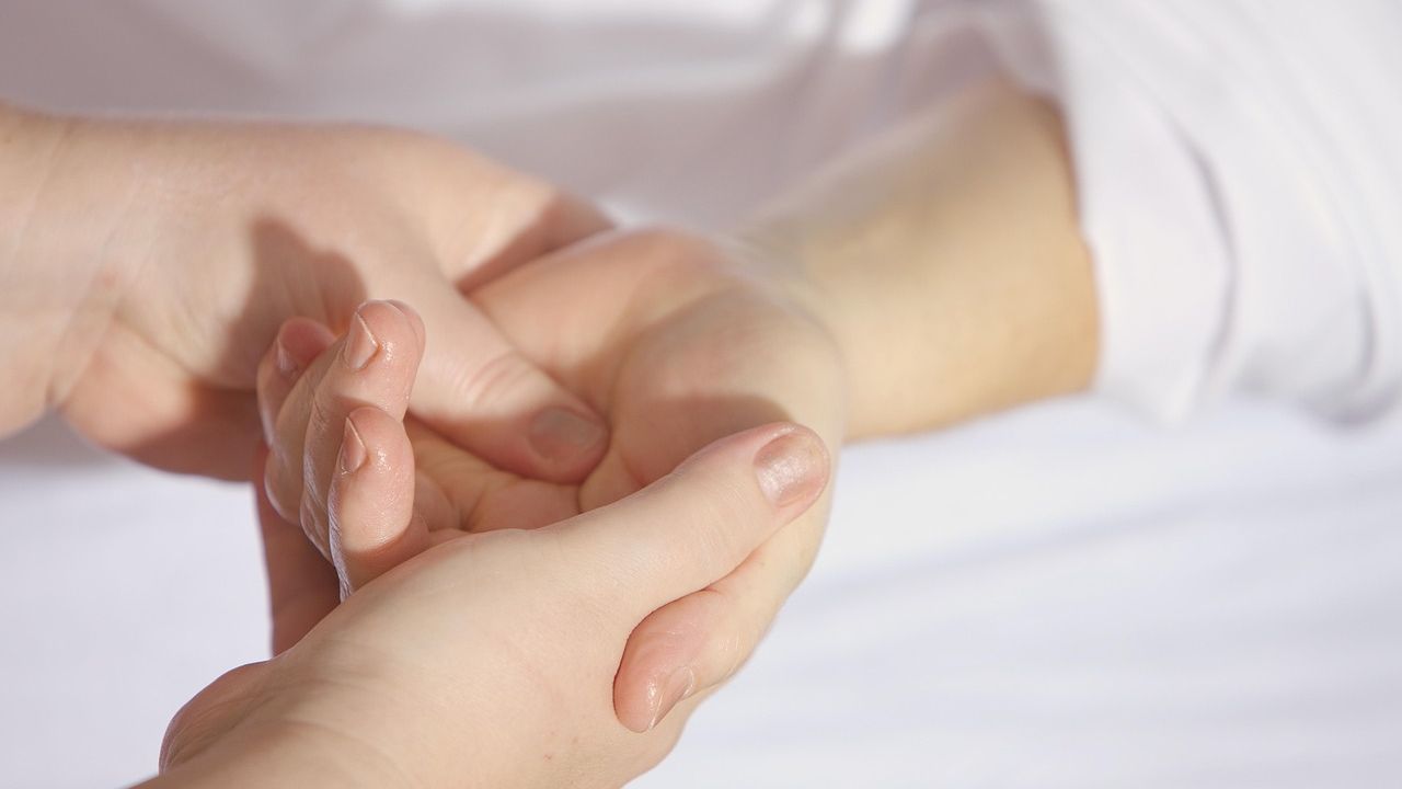 Therapist gently massaging a client's hand