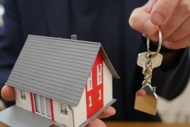 Agent handing over house keys beside a model house