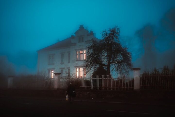 Old house shrouded in blue fog at night