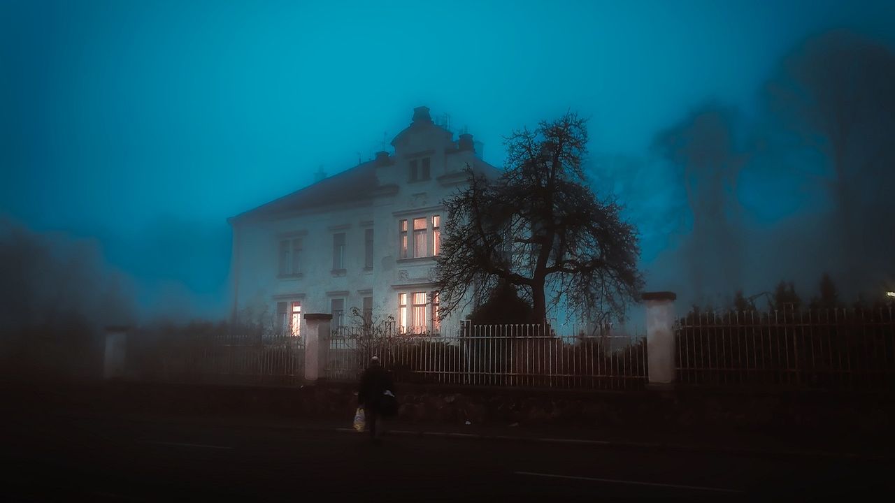 Old house shrouded in blue fog at night
