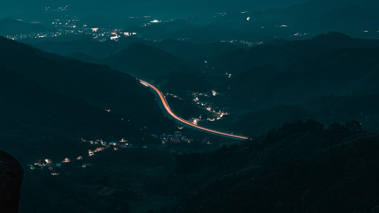 Night landscape, mountains, highway, light trail, landscape at night, nature, hilly area, city lights, road lights, panoramic shot, peaceful night, distant view, quiet landscape, long exposure, mountain silhouette, small town, peaceful atmosphere, rural landscape, night driver, cityscape, quiet evening