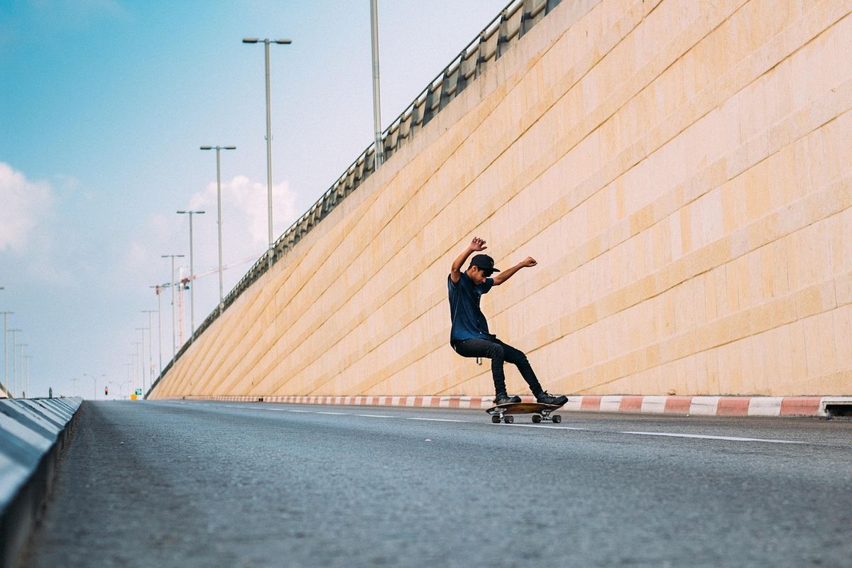 Skateboarder riding along an empty road